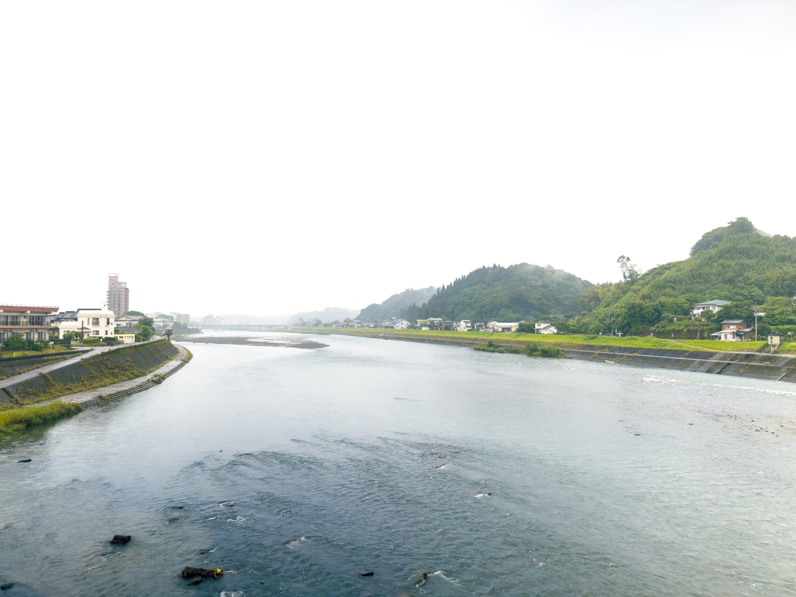 豪雨で増水した川、両岸の町並みの傍にまで迫る水