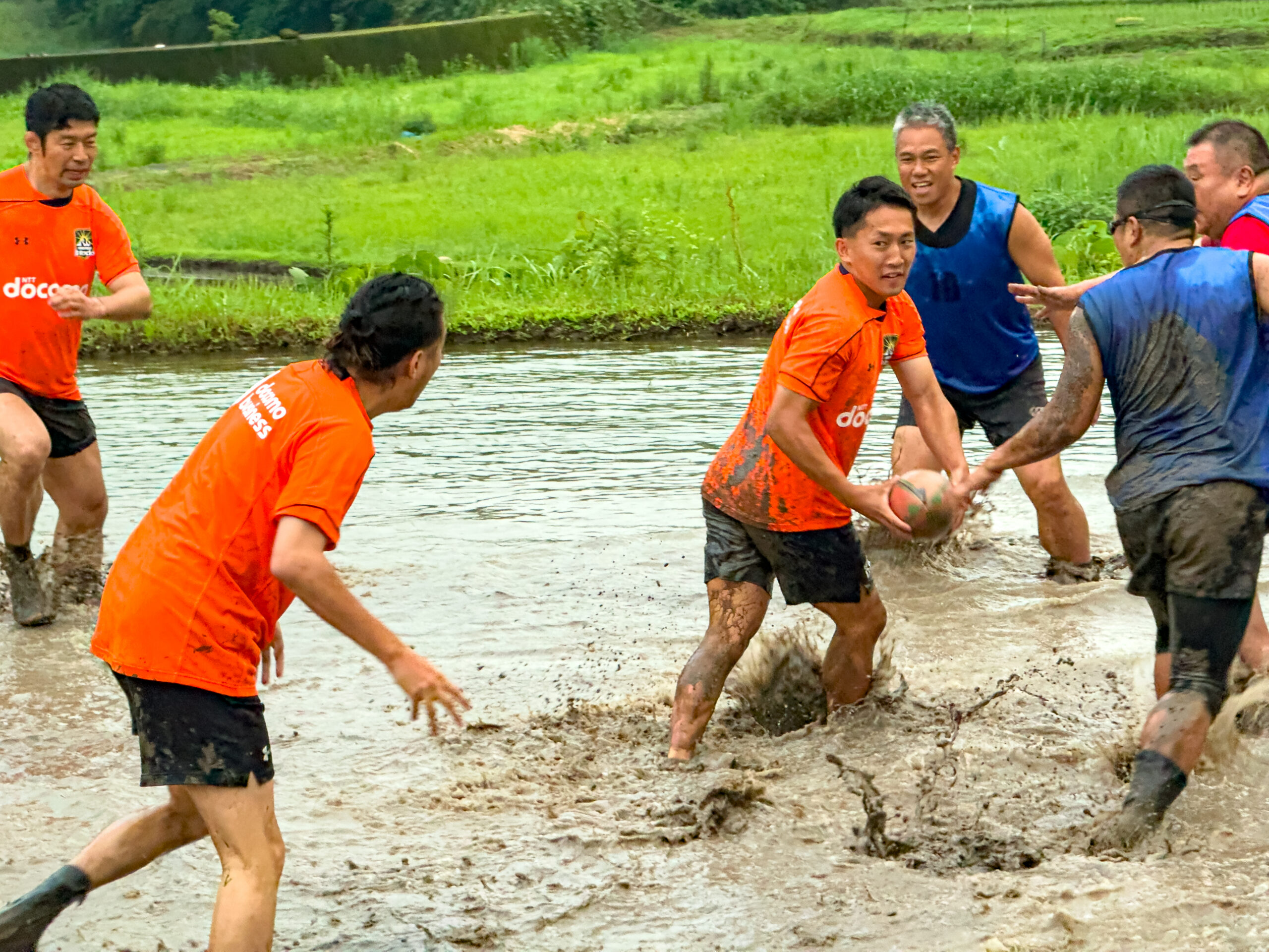 水を張った田んぼでパスをつなぐ田んぼラグビーの選手たち
